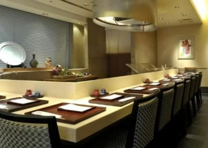 The counter seats at Tempura Kondo, with dark trays contrasting against the beige counter.